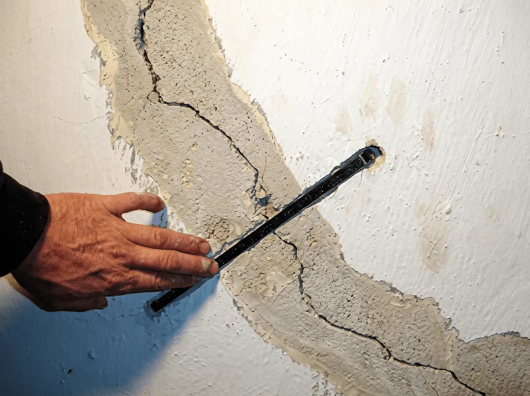 A wall with a large crack is being inspected by a professional in Clearwater, FL